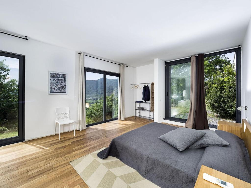 une chambre avec un grand lit et de grandes fenêtres dans l'établissement Villa Alcantara, à Gaggi