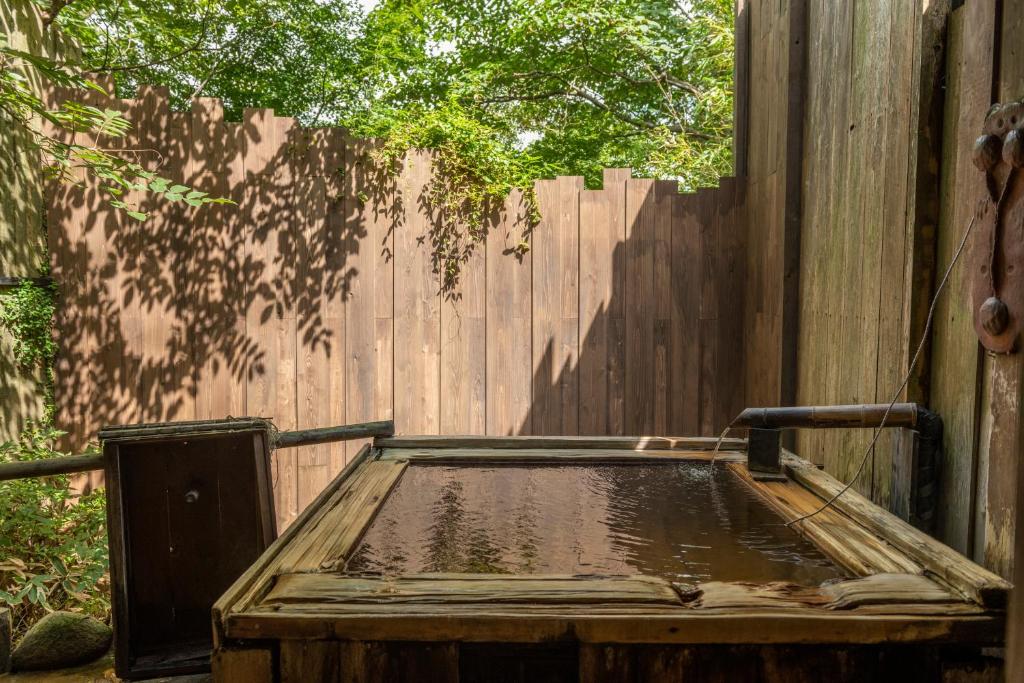 une clôture en bois avec une table en bois devant elle dans l'établissement Setsugetsuka, à Hakone