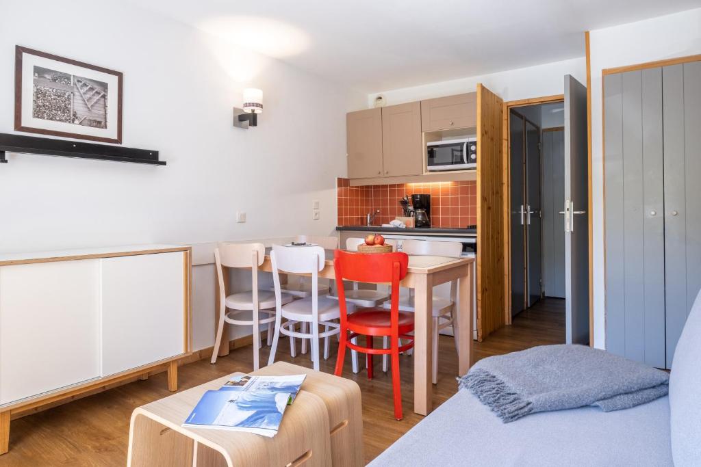 Ce petit appartement comprend une cuisine, une table et des chaises. dans l'établissement Résidence Pierre & Vacances Le Machu Pichu, à Val Thorens
