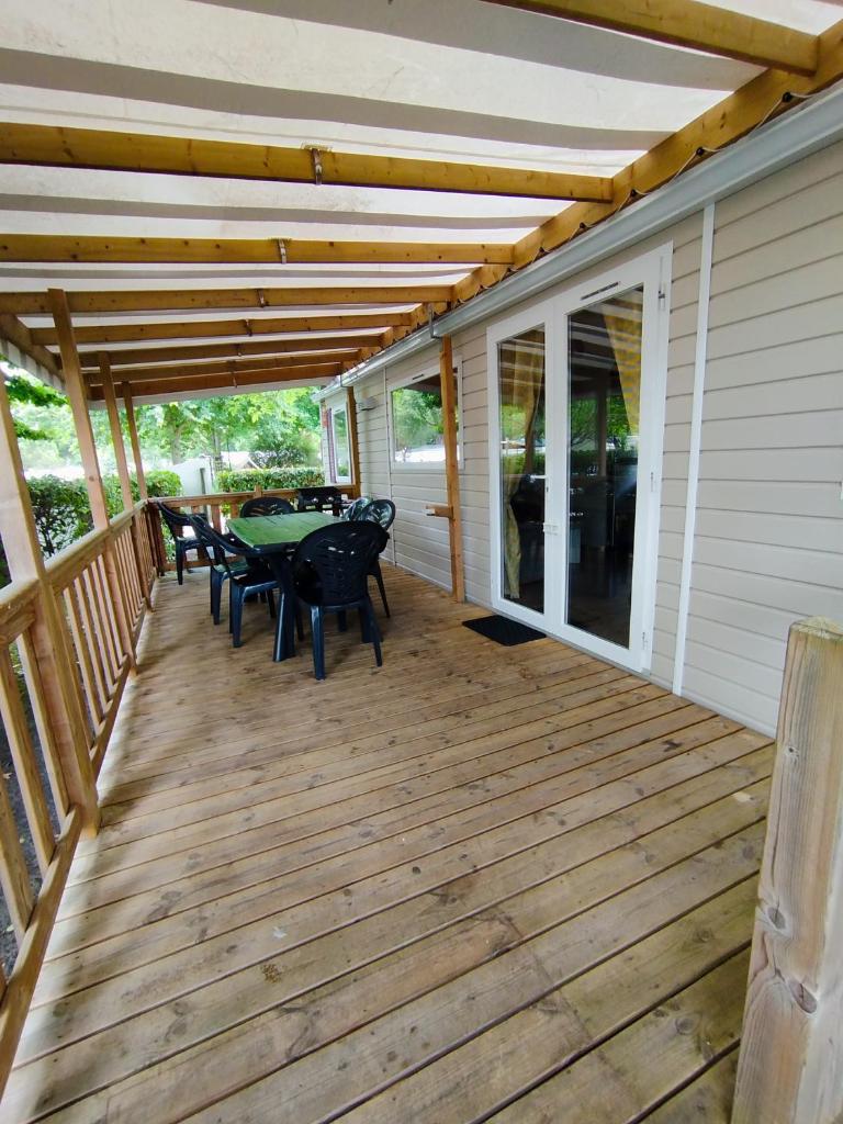 une terrasse en bois avec une table et des chaises dessus dans l'établissement Mobil-home, à Gastes