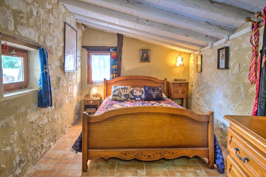 - une chambre avec un lit en bois dans un mur en pierre dans l'établissement Le Magicogite - Harry Potter, à Larocal
