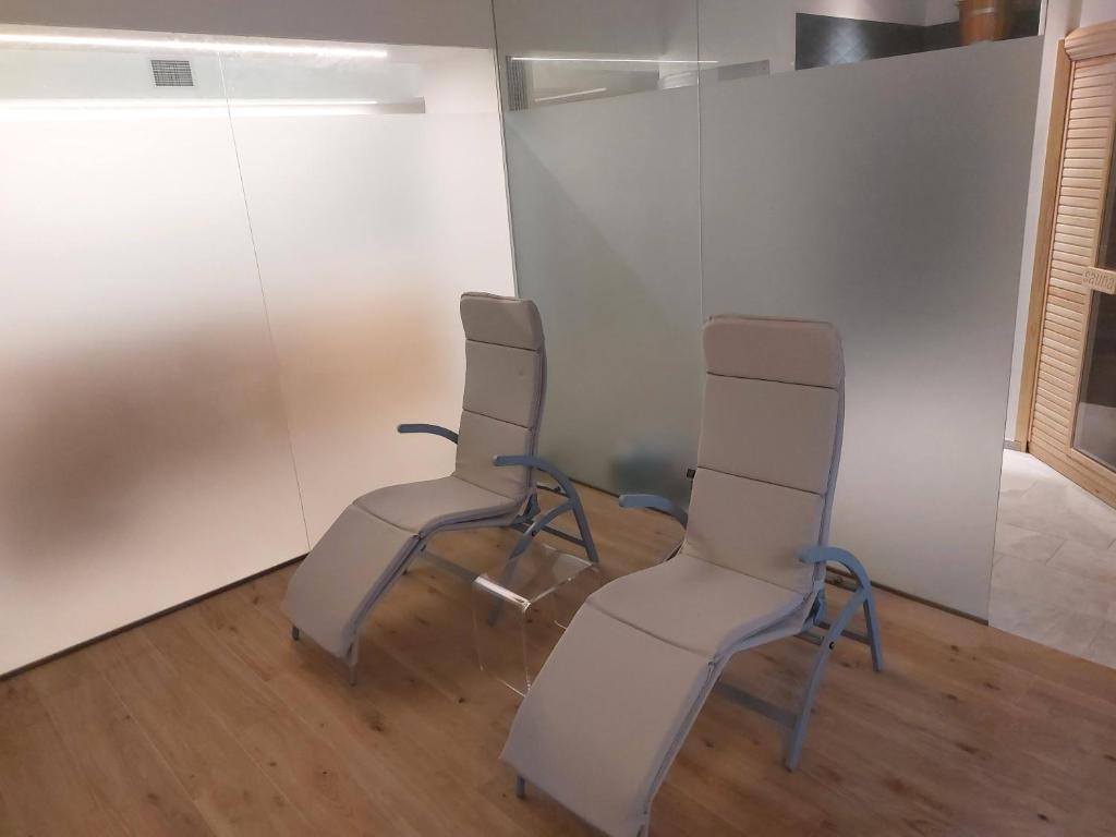 2 chaises dans une chambre aux murs blancs dans l'établissement Residence Aurora Wellness & Spa, à Albenga