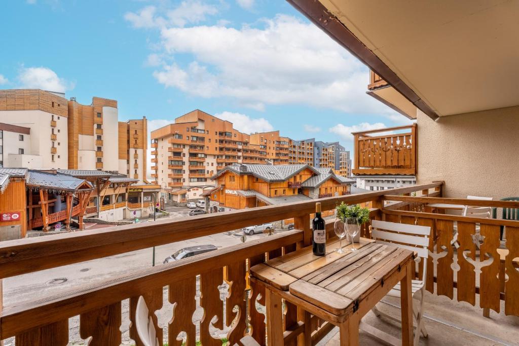 d'un balcon avec un banc en bois et une vue sur la ville. dans l'établissement Ski In-Out - Heart of Val Thorens Convenient Flat, WiFi 92, à Val Thorens