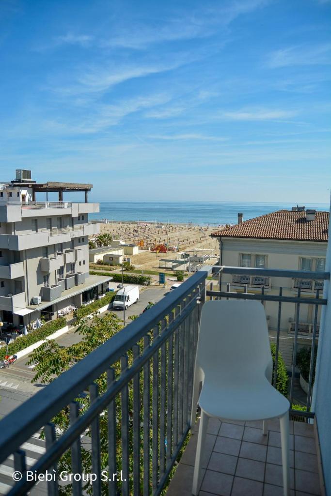 un balcon avec une chaise blanche et une vue sur l'océan dans l'établissement Hotel Giorg - WaterPark Free Entrance, à Rimini