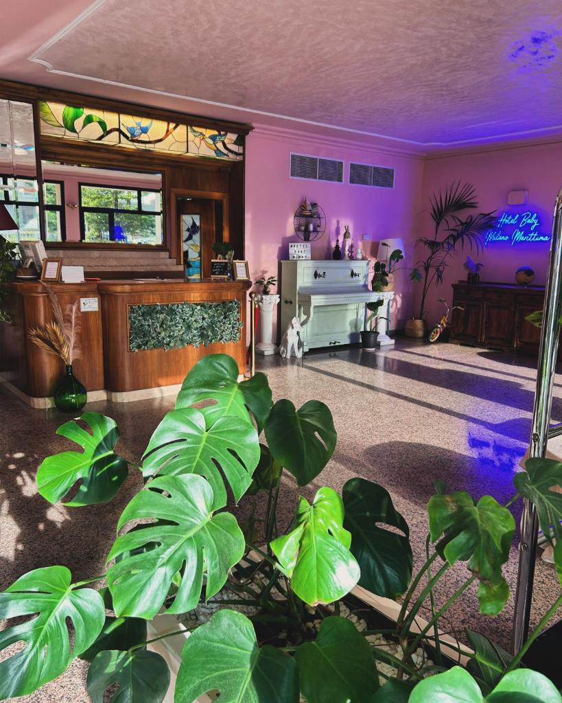 un salon avec des plantes vertes et des murs violets dans l'établissement Hotel Baby B&B, à Milano Marittima