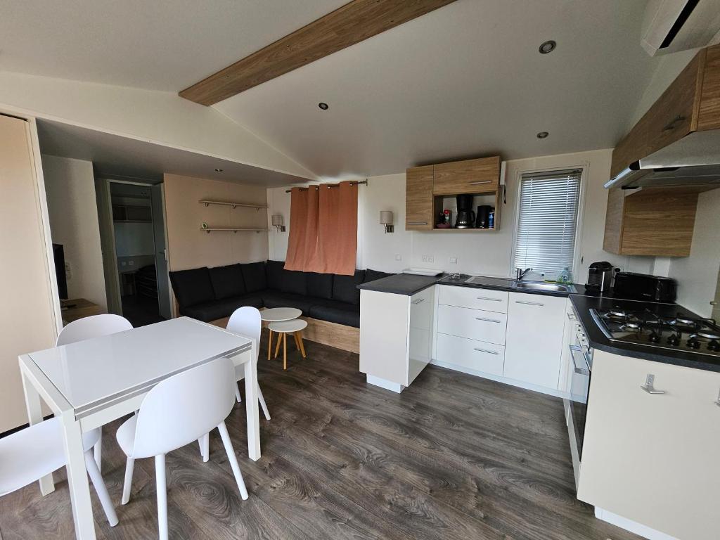 une cuisine avec des armoires blanches et une table et des chaises dans l'établissement Mobilhome L'Estérel du Montourey, à Fréjus