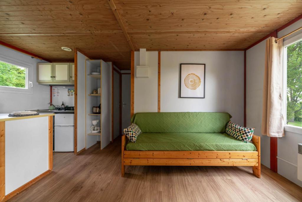 - un canapé vert dans une pièce avec cuisine dans l'établissement Camping Le Mont Libre - Cottage & espace nature - Gannat, à Gannat