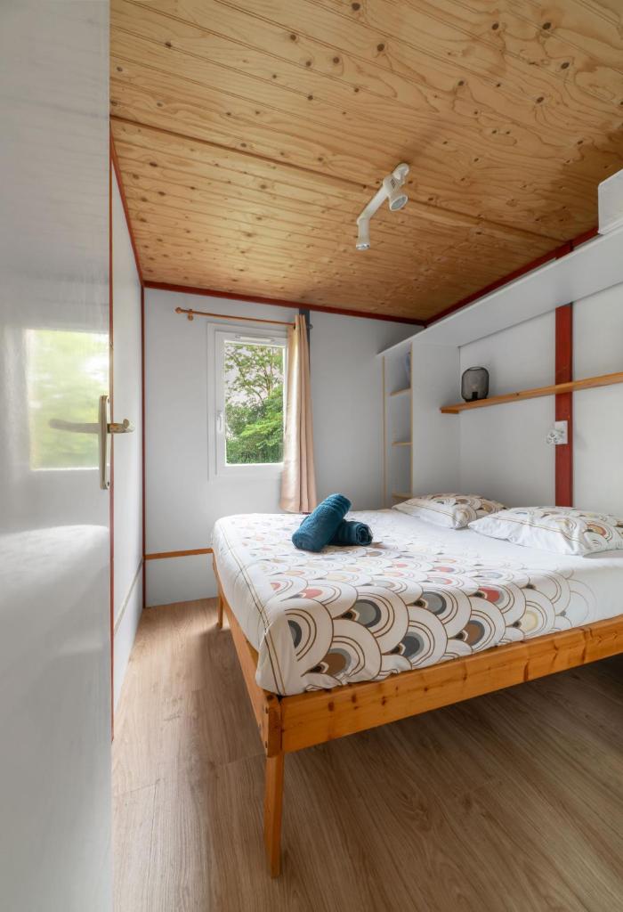 une chambre avec un lit avec un plafond en bois dans l'établissement Camping Le Mont Libre - Cottage & espace nature - Gannat, à Gannat 37 autres photos