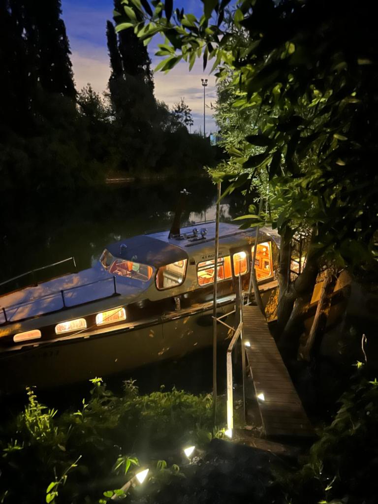 un bateau est garé à côté d'un quai la nuit dans l'établissement Séjour insolite sur un bateau, à Louveciennes