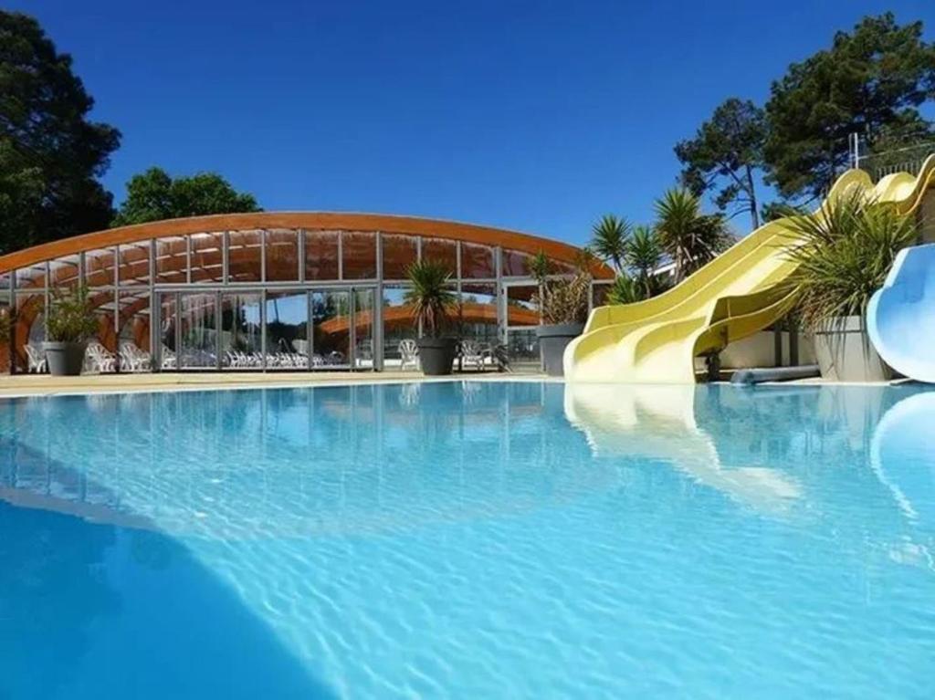 une piscine avec toboggan en face d'un bâtiment dans l'établissement Mobile Home Lège-Cap-Ferret, à Lège-Cap-Ferret