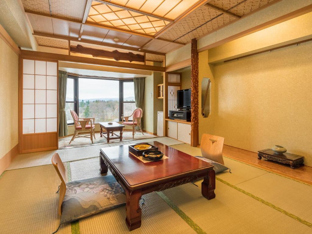 un salon avec une table et des chaises en bois dans l'établissement New Akan Hotel, à Akankohan