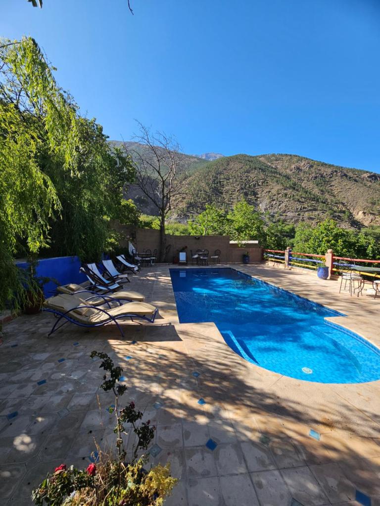 - une piscine avec des chaises, une table et une montagne dans l'établissement Jnane Karma, à Imlil
