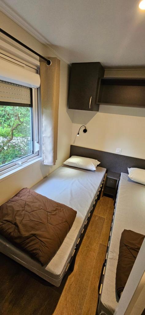 deux lits dans une chambre avec une fenêtre dans l'établissement Mobil-Home 3 chambres - Camping Les Ollivaud, à La Baule 5 autres photos