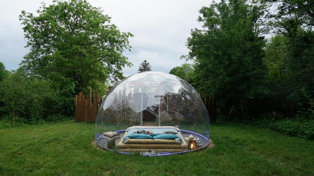 un dôme de verre avec un lit dans l'herbe dans l'établissement Ô Pays Des Bois - Hébergements insolites en pleine nature, à Parmilieu