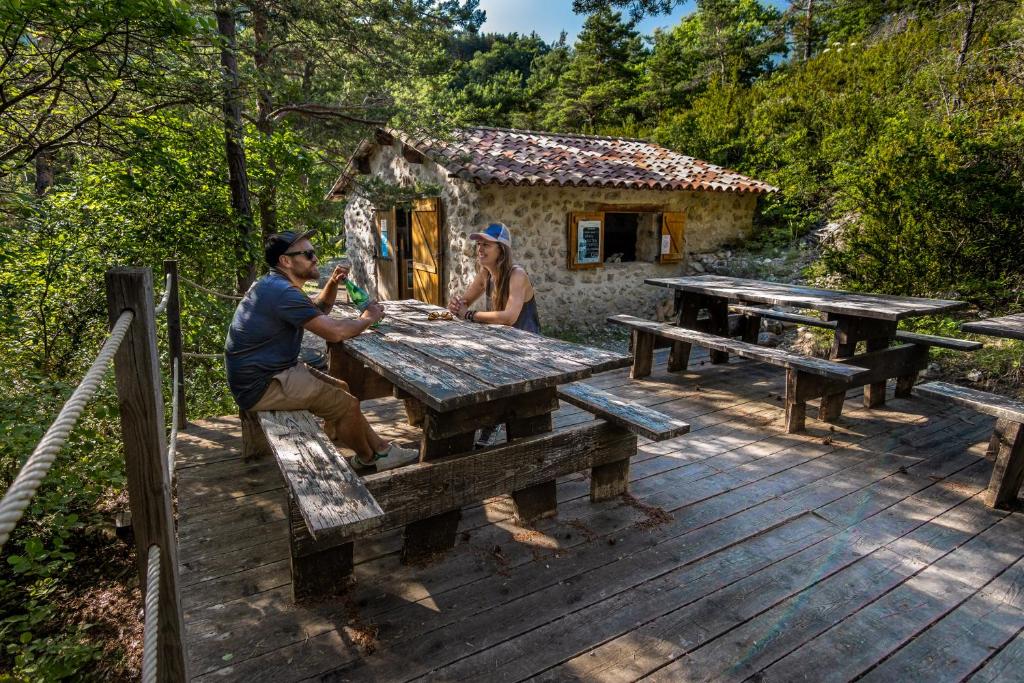 un homme et une femme assis à une table de pique-nique sur une terrasse dans l'établissement Adventure Forest, à Castellane