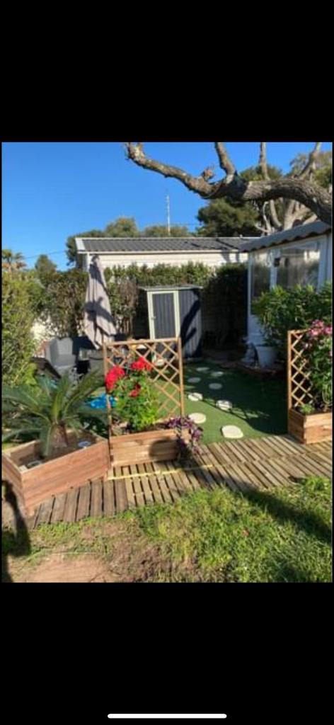 une cour arrière avec une terrasse en bois avec des fleurs et une maison dans l'établissement L éden, à Hyères