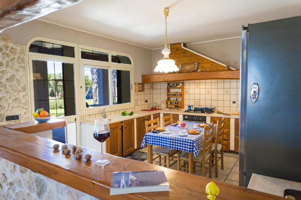 - une cuisine avec une table et un verre de vin dans l'établissement Villa El Capitano With Garden And Pool - Happy Rentals, à Muro Leccese