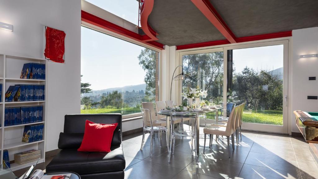 une salle à manger avec une table et des chaises et une grande fenêtre dans l'établissement VILLA DADA 10, Emma Villas, à Rosignano Marittimo