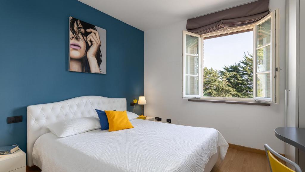- une chambre avec un lit blanc et un mur bleu dans l'établissement VILLA DADA 10, Emma Villas, à Rosignano Marittimo