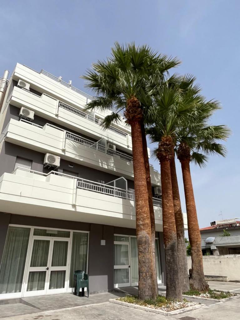 un bâtiment avec des palmiers devant dans l'établissement Hotel Mediterraneo, à Martinsicuro