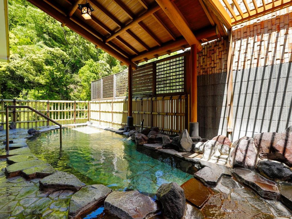 une piscine d'eau avec des rochers devant un bâtiment dans l'établissement Hakone Pax Yoshino, à Hakone