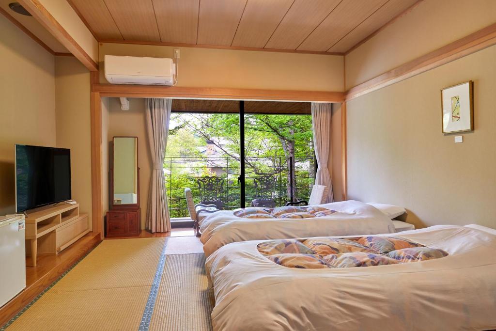 Cette chambre comprend une rangée de lits et une télévision. dans l'établissement IKOI Villa, à Karuizawa