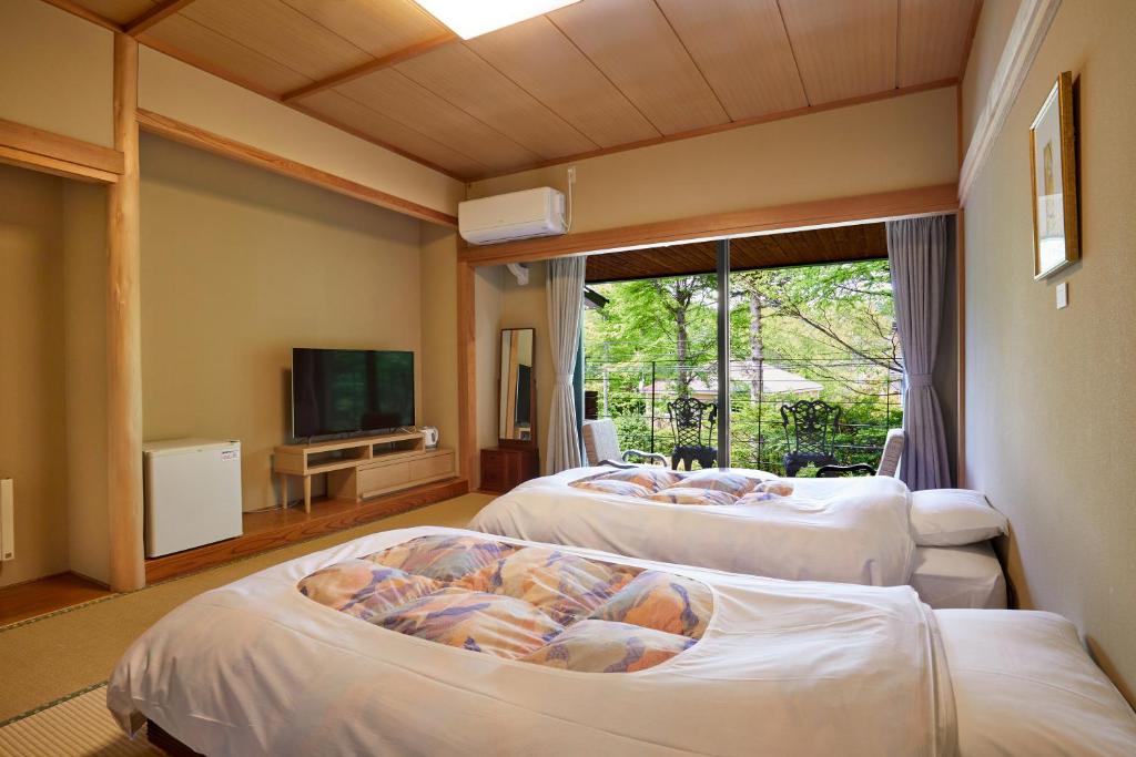 - 2 lits dans une chambre avec une télévision et une chambre dans l'établissement IKOI Villa, à Karuizawa