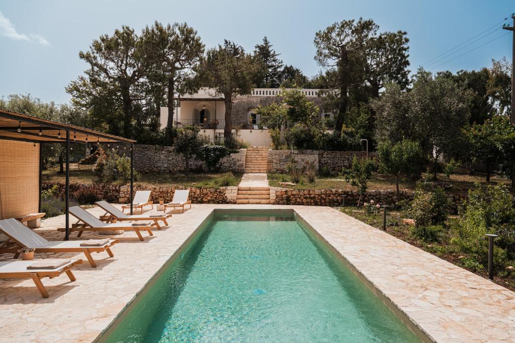 une piscine avec des chaises et une maison en arrière-plan dans l'établissement HelloApulia Il Mirteto, à Selva di Fasano
