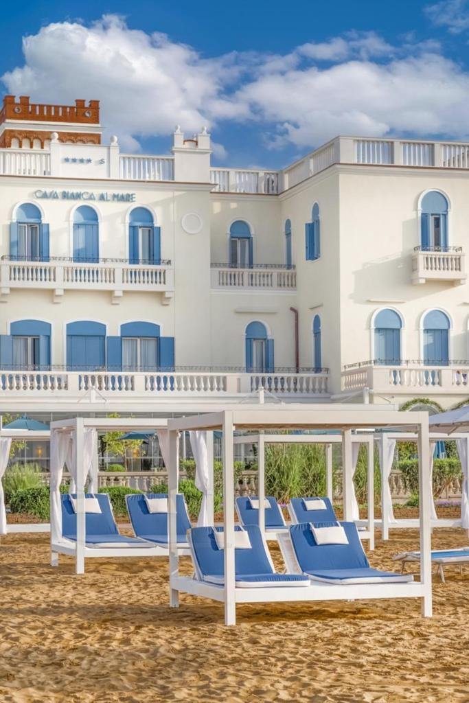 une rangée de chaises de plage devant un hôtel dans l'établissement Casa Bianca Al Mare, à Lido di Jesolo