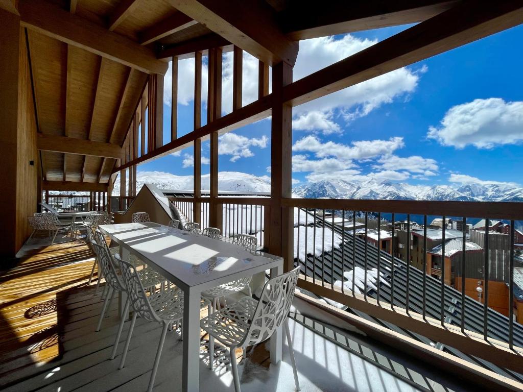 d'un balcon avec une table, des chaises et des montagnes. dans l'établissement Homency - Résidence Phoenix B46, à L'Alpe-d'Huez