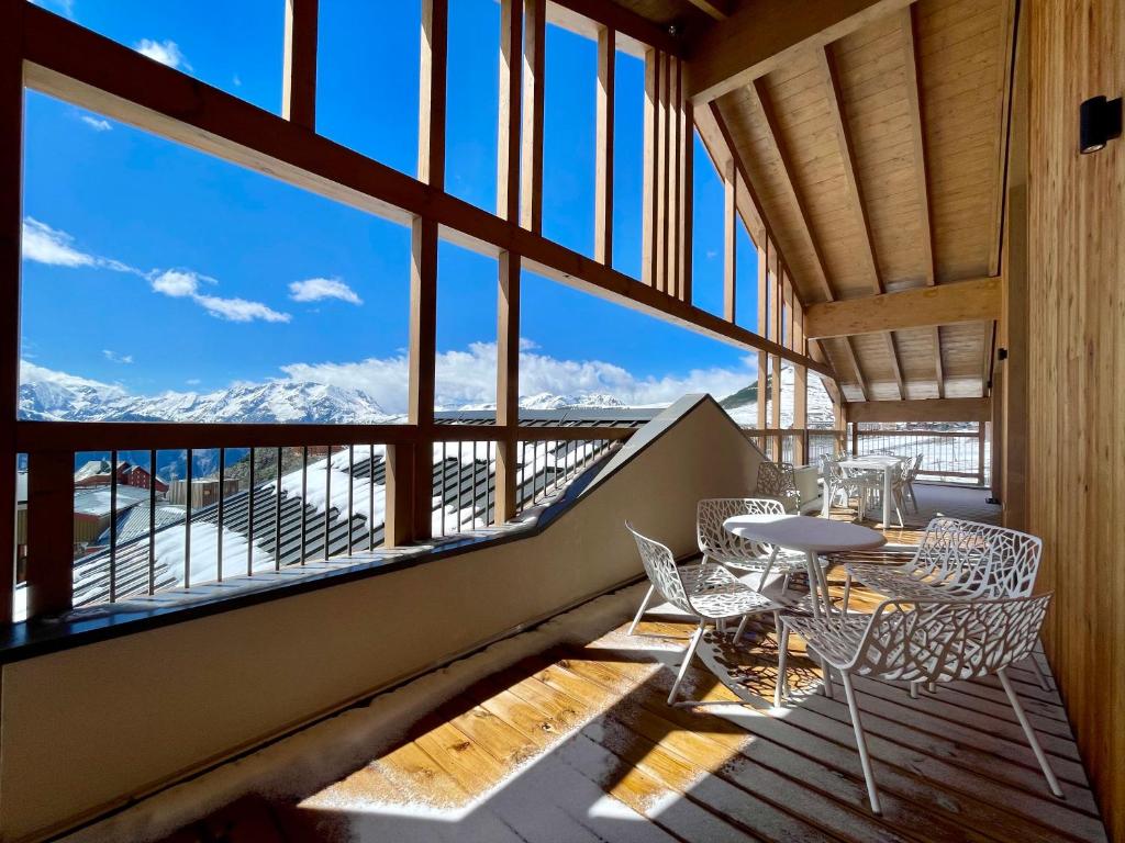 d'un balcon avec des tables et des chaises et une vue sur les montagnes. dans l'établissement Homency - Résidence Phoenix B46, à L'Alpe-d'Huez