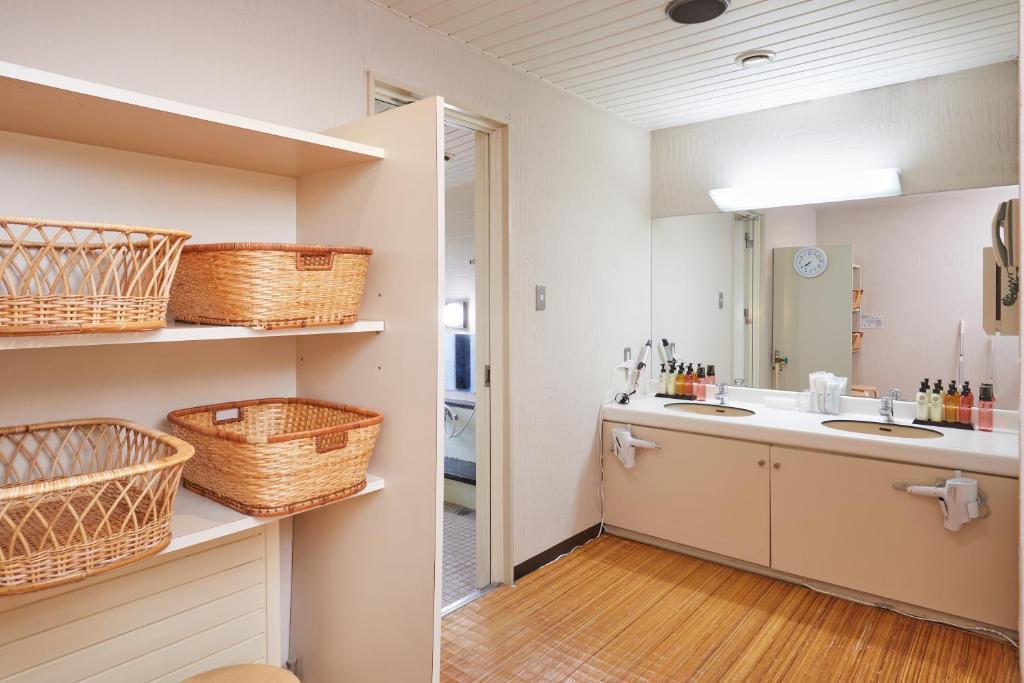 une salle de bain avec un lavabo et des paniers sur les étagères dans l'établissement IKOI Villa, à Karuizawa