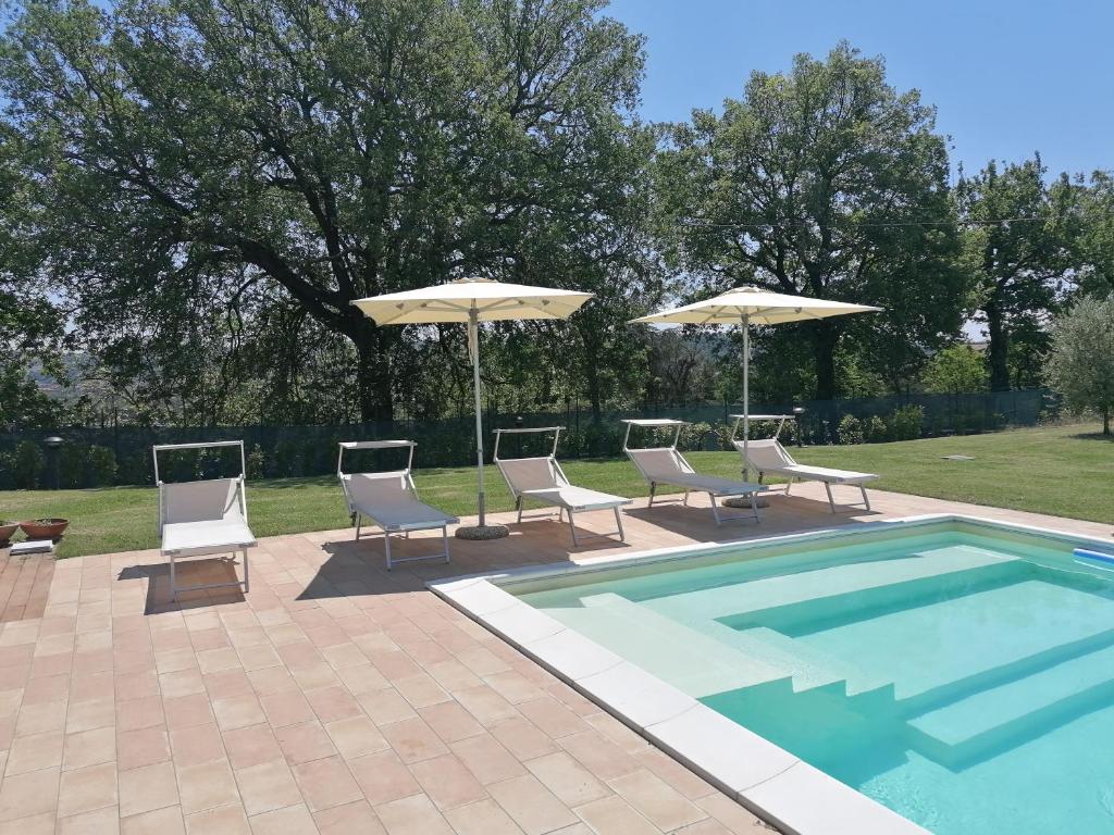 une terrasse avec des chaises et des parasols ainsi qu'une piscine dans l'établissement Relais Villa Sofia, à Calcinelli