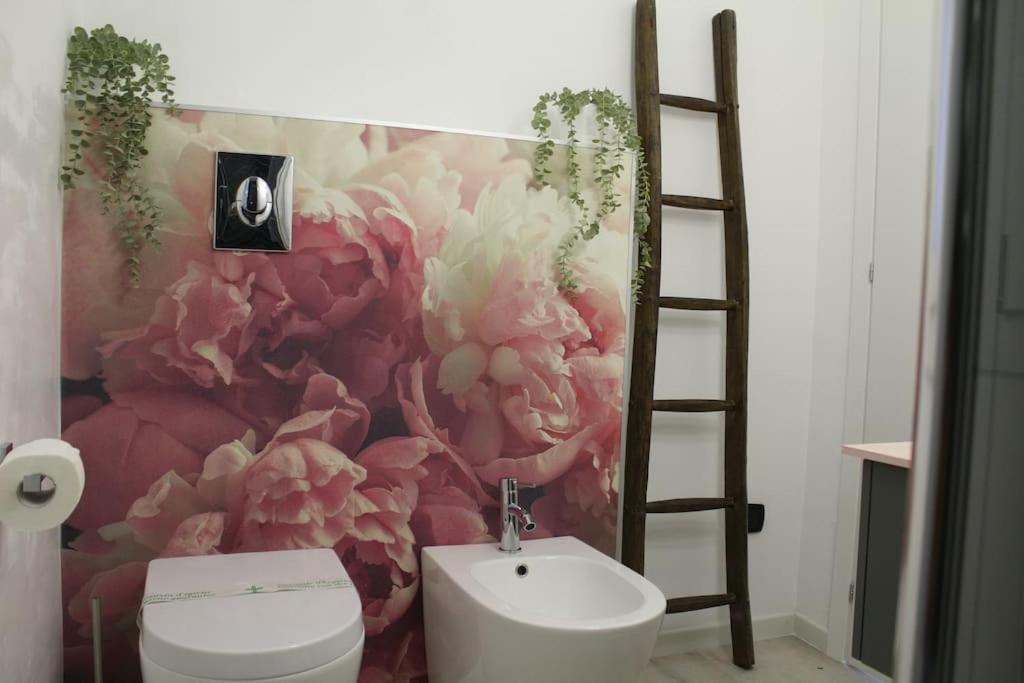 La salle de bains est pourvue de toilettes et d'une fresque florale. dans l'établissement Conca Verde c15-Beach front little villa POOL SPA BEACH, à Marina dʼAndora