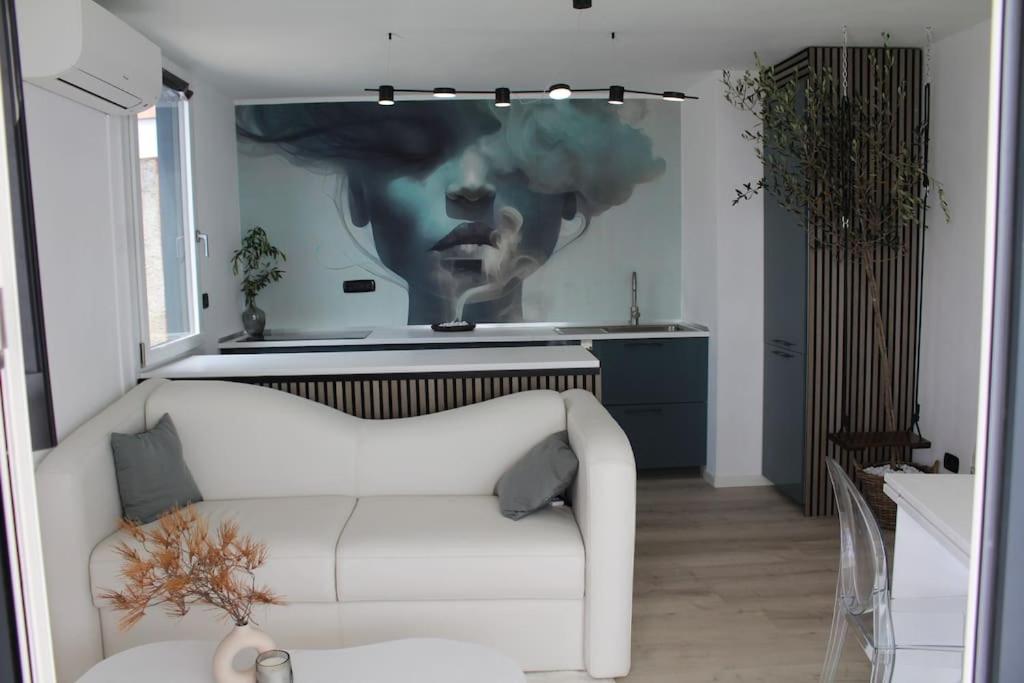 un salon avec un canapé blanc et un tableau mural dans l'établissement Conca Verde c15-Beach front little villa POOL SPA BEACH, à Marina dʼAndora
