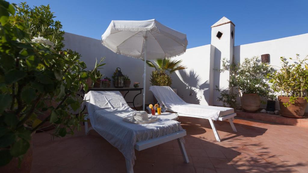 - une terrasse avec 2 chaises blanches et un parasol dans l'établissement Riad Les Orangers D'alilia, à Marrakech