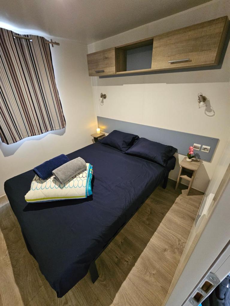 une chambre avec un grand lit avec des draps bleus dans l'établissement Mobil home climatisé 6 pers, au Muy