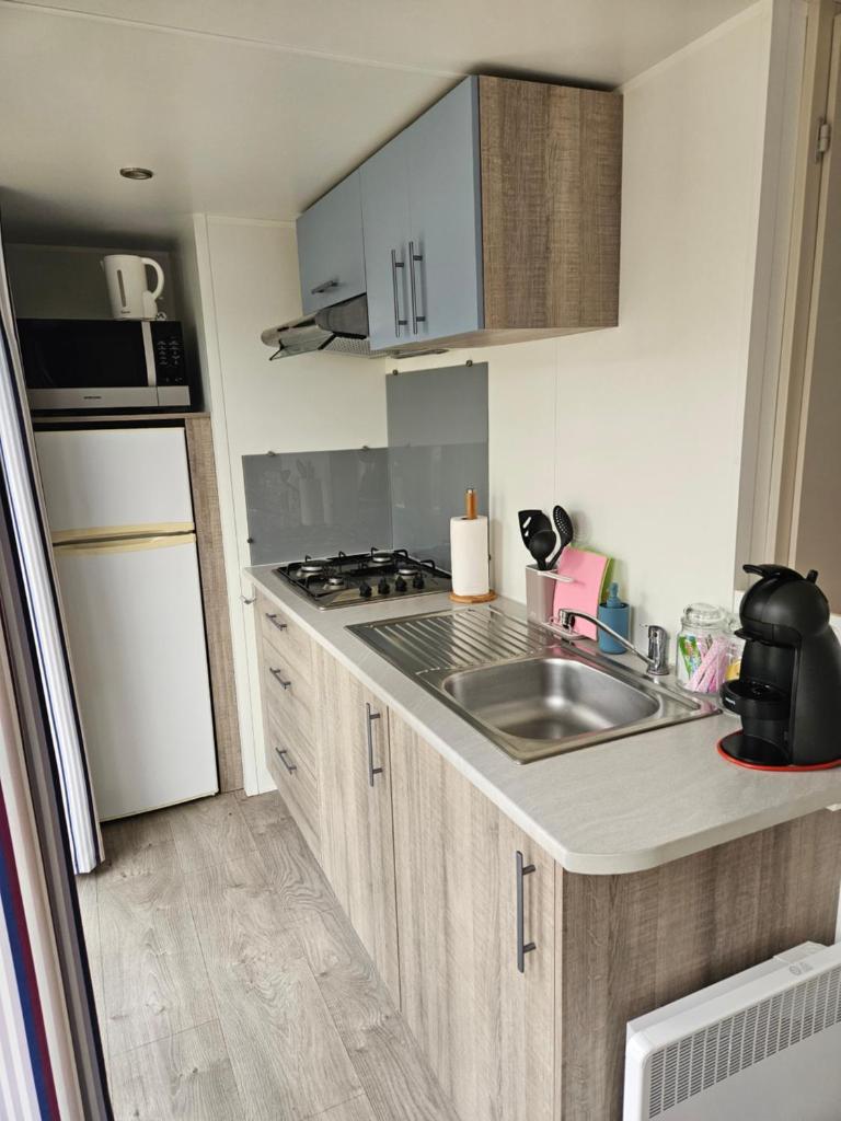 une cuisine avec un évier et une cuisinière four supérieur dans l'établissement Mobil home climatisé 6 pers, au Muy