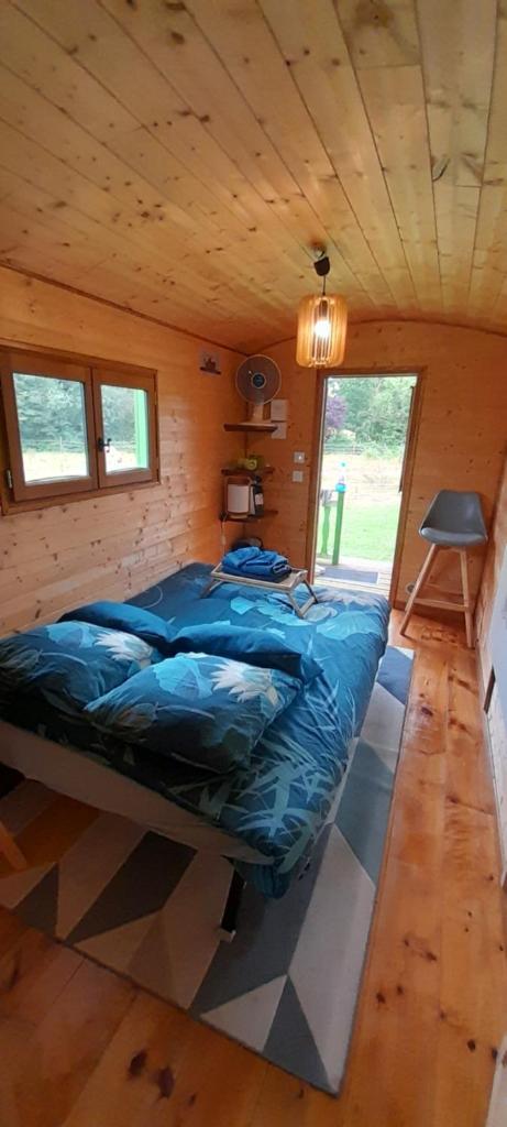 une chambre avec un lit dans une cabane en bois dans l'établissement Roulotte verte, à Pouilly-sur-Vingeanne
