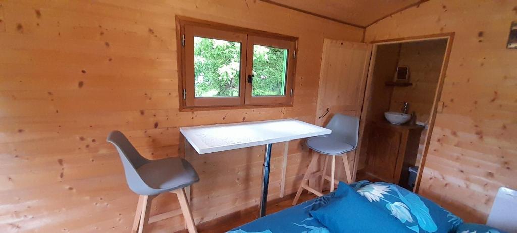 une pièce avec un bureau et deux chaises dans une cabine dans l'établissement Roulotte verte, à Pouilly-sur-Vingeanne