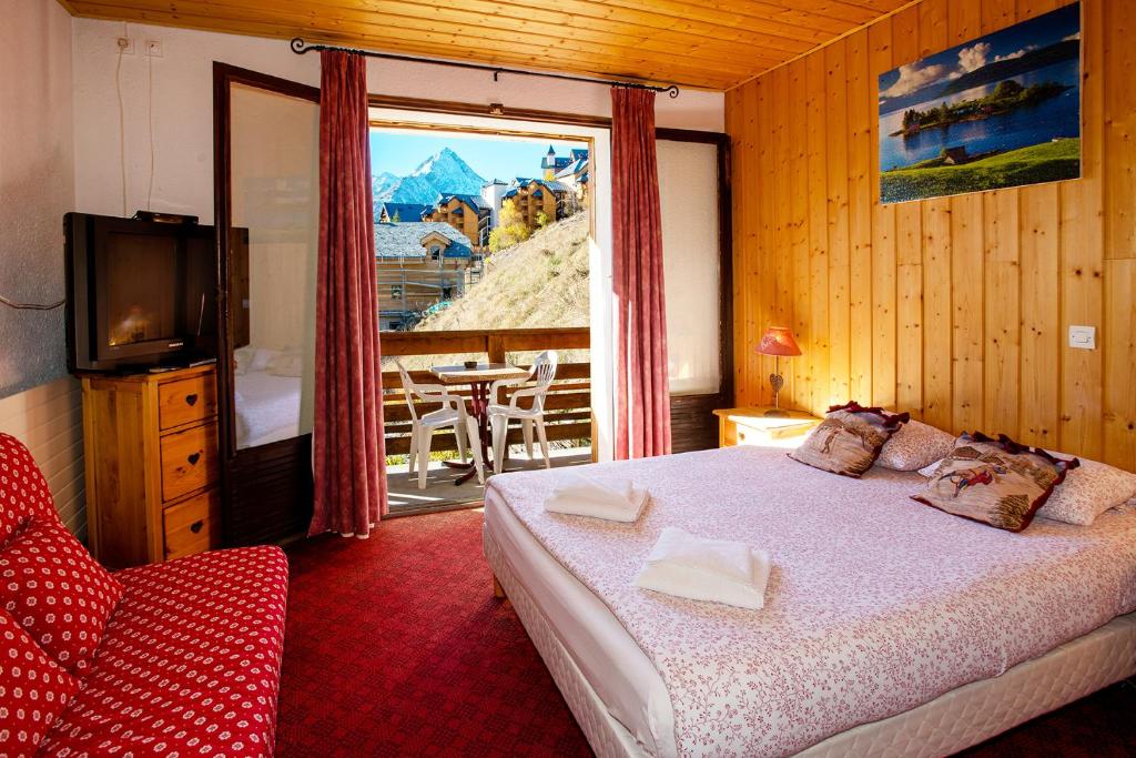 une chambre avec un lit et un balcon avec une table dans l'établissement Hotel Le Cairn, à Les Deux Alpes