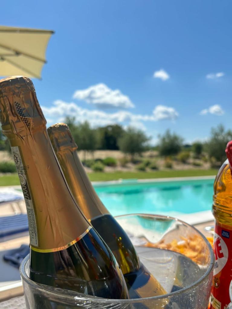 deux bouteilles de champagne dans un bol en verre à côté d'une piscine dans l'établissement Relais Villa Sofia, à Calcinelli