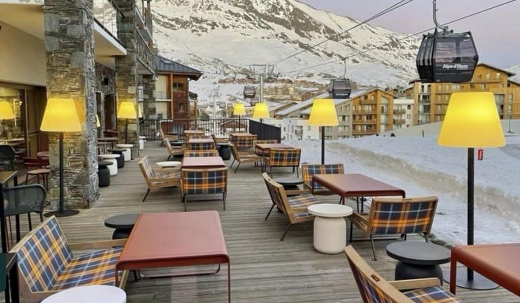 d'une terrasse avec des tables, des chaises et des montagnes enneigées. dans l'établissement Homency - Résidence Daria-i-Nor 202, à L'Alpe-d'Huez