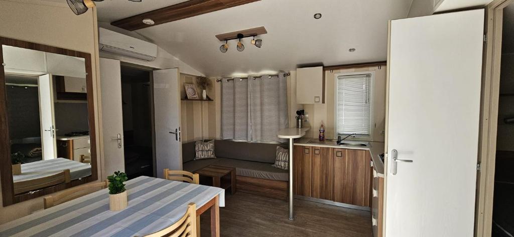 une cuisine et un salon avec une table et une salle à manger dans l'établissement Mobil home 6 personnes confort Océan climatisé camping avec piscine Agde, à Agde