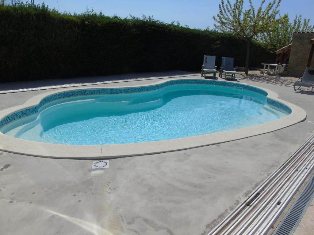 une grande piscine entourée de 2 chaises dans l'établissement Gite aux Lauriers d'Adhémar, à La Garde-Adhémar
