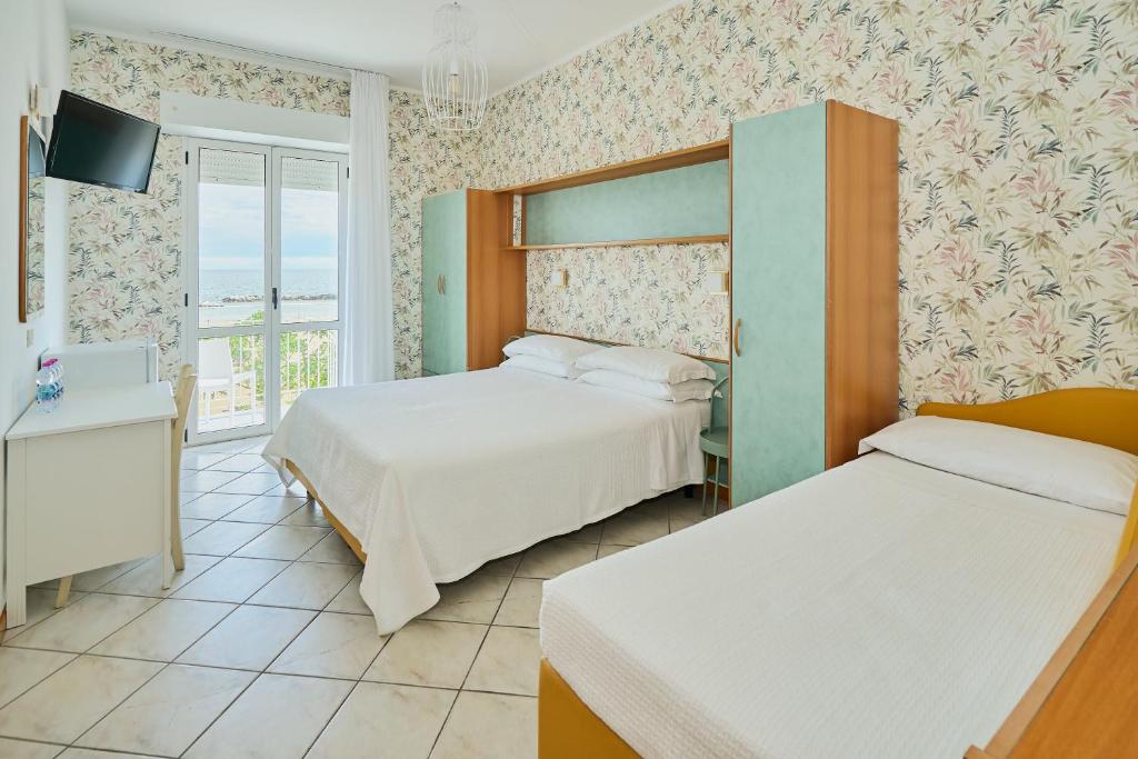 une chambre d'hôtel avec deux lits et une télévision dans l'établissement Hotel Acquario, à Rimini