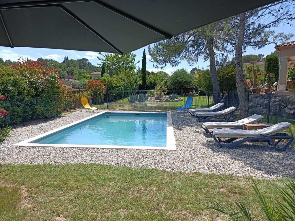 une piscine avec deux chaises longues et un parasol dans l'établissement Anduze Gîte Les Pins au "Petit Clos des Cigales", à Massillargues-Attuech