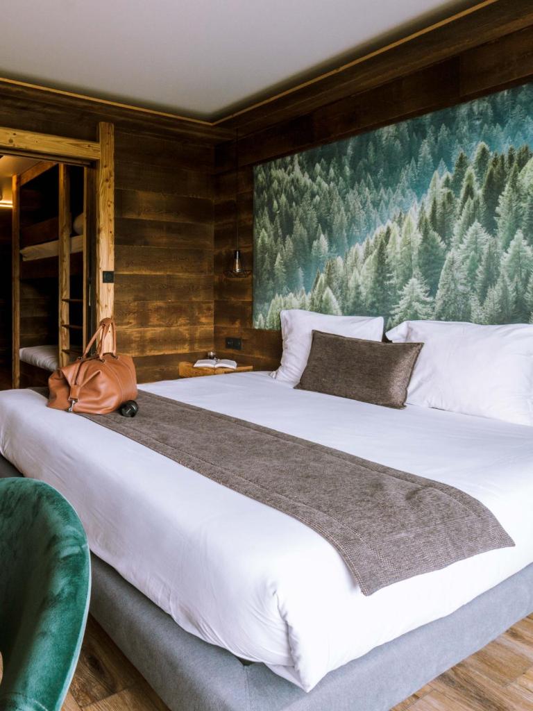 - une chambre avec un grand lit blanc orné d'une peinture murale dans l'établissement La Perelle, à Saint-François-Longchamp 25 autres photos