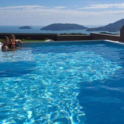 2 personnes se baignant dans une grande piscine bleue dans l'établissement Colori di Mare Luxury Holiday, à Lerici