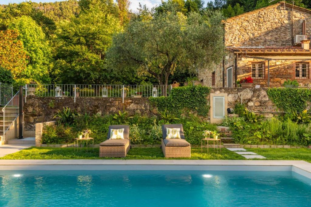 une maison avec deux chaises et une piscine dans l'établissement Villa Ester, a Stylish Farmhouse on the Hills, à Capannori